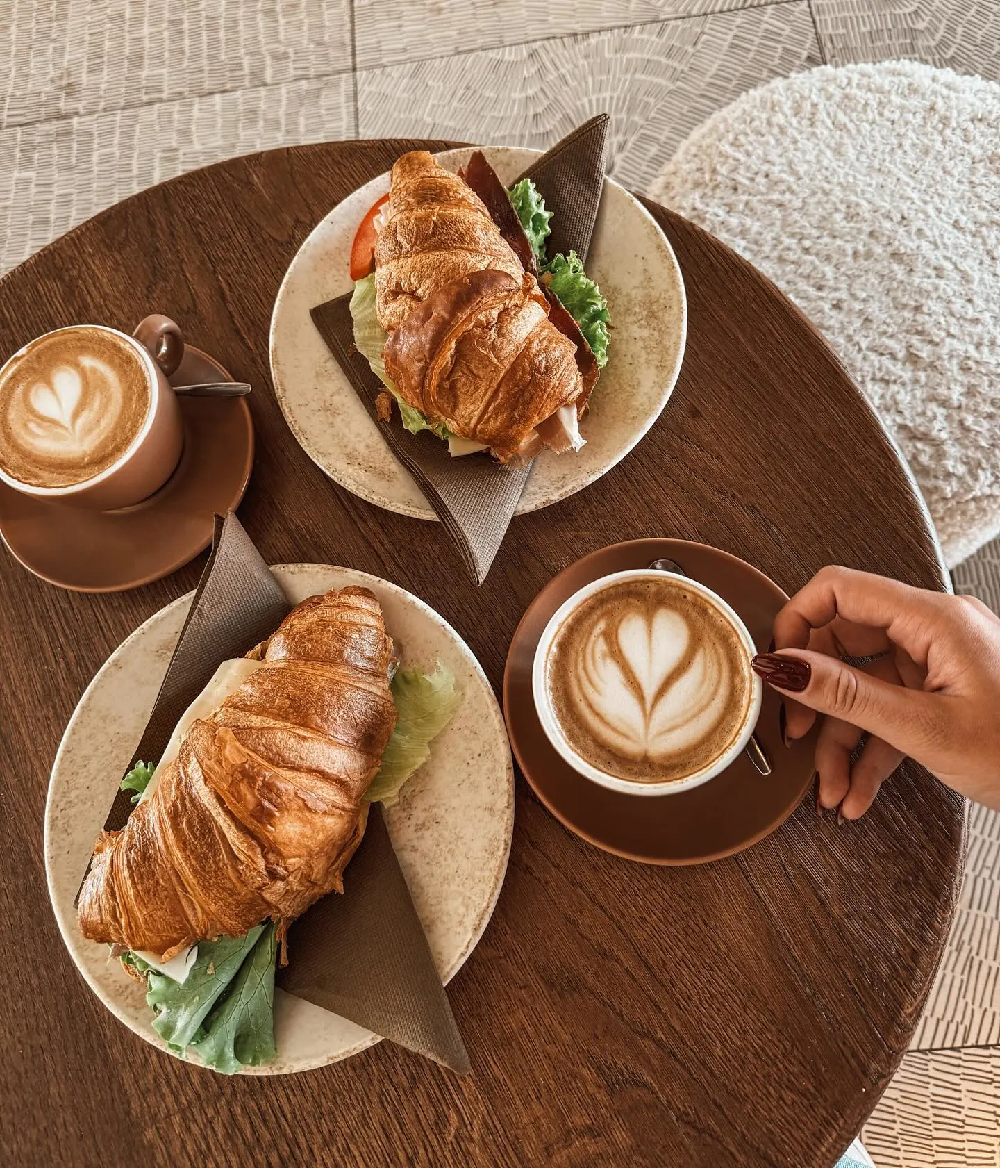 Croissant sandwiches and latte art coffee on wooden table - perfect breakfast atmosphere