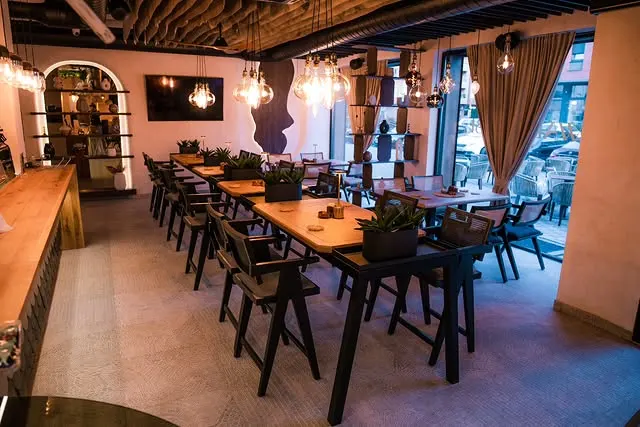 Wabi Sabi café interior with long wooden tables, pendant lights, and modern minimalist design
