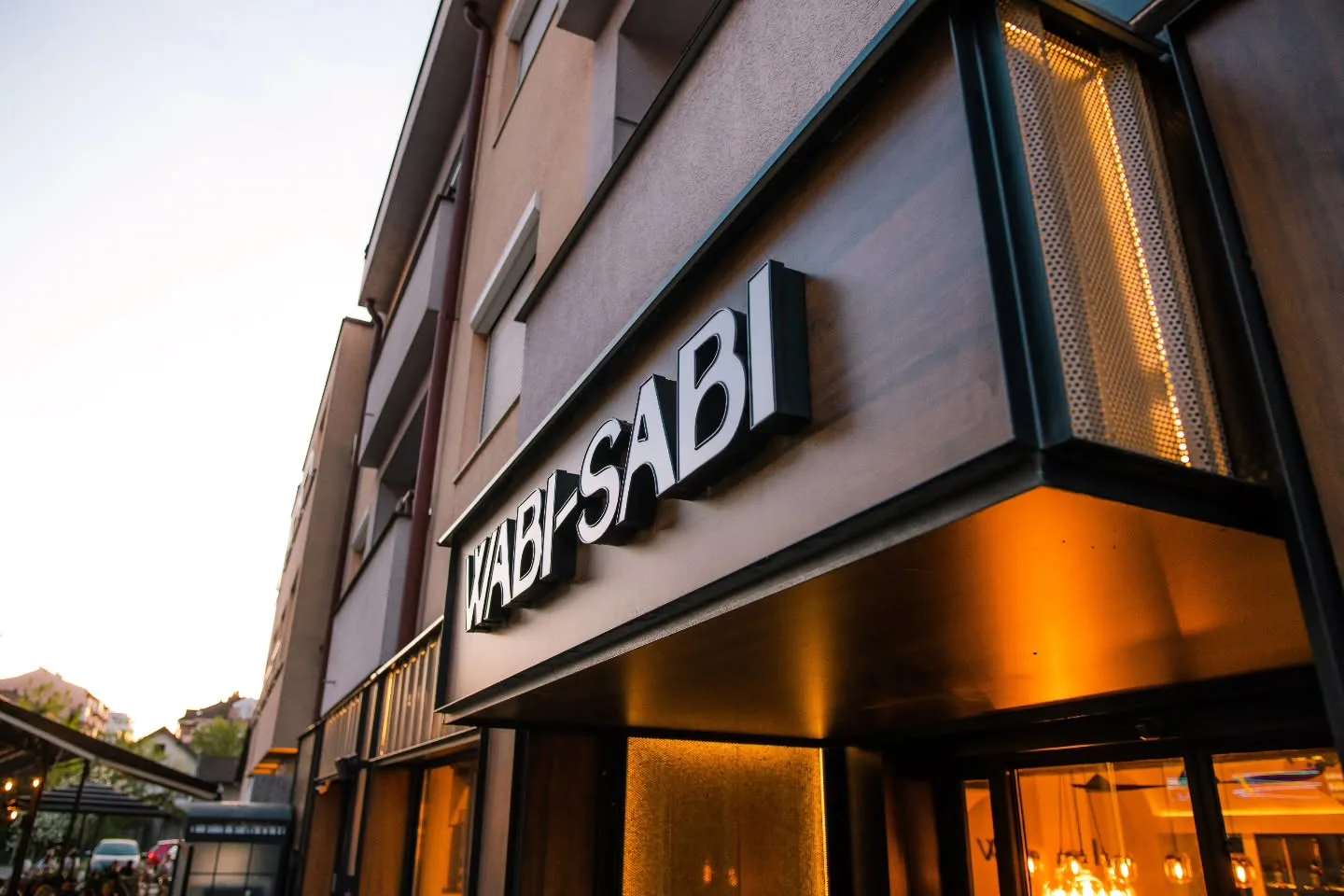 Wabi Sabi café exterior at evening with warm golden lighting and modern architecture