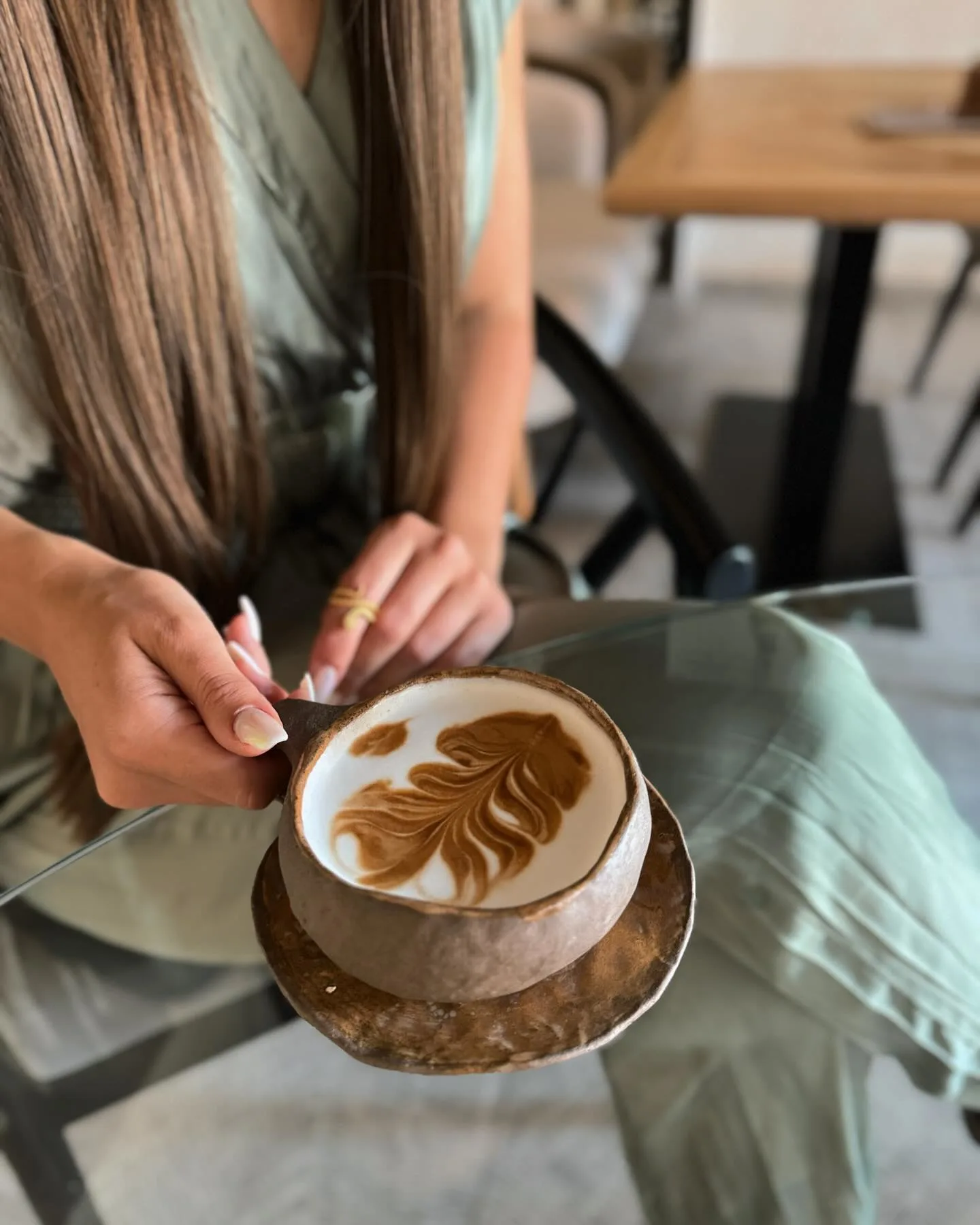 Beautiful cappuccino with rosette latte art held by woman - artisan coffee craftsmanship